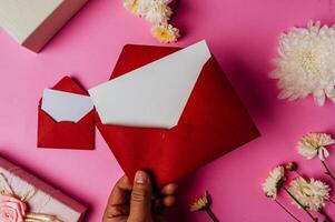 sobre rojo, caja de regalo rosa con tarjeta en blanco y flor foto