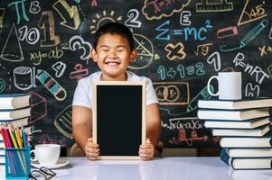 Child sitting and holding blackboard in the classroom photo