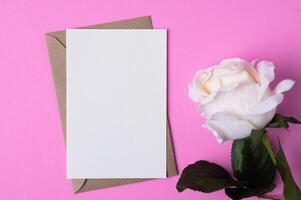 papel en blanco con flores colocadas sobre un fondo rosa foto