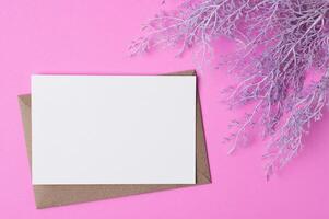 Blank paper with flowers placed on a pink background photo