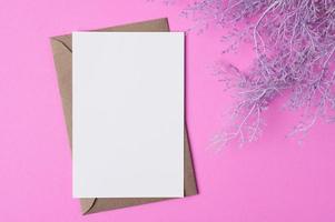 Blank paper with flowers placed on a pink background photo