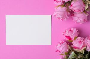 papel en blanco con flores colocadas sobre un fondo rosa foto