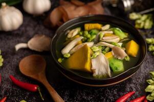Kaeng Liang in a bowl with spices on a black cement floor. photo