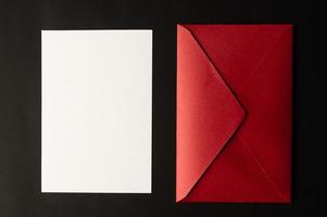 se colocan papel blanco y un buzón rojo sobre un fondo negro. foto