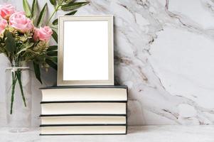 un marco de fotos colocado sobre un libro con un jarrón de flores