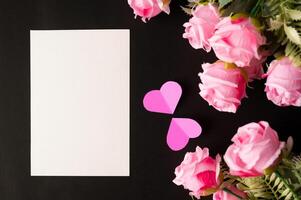 White paper and pink flowers pasted on a black background photo