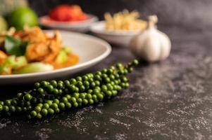 Curry verde seco con pollo en placas blancas sobre cemento negro foto