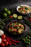 Pork green curry in a brown bowl with spices on a black cement photo