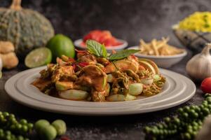 Dry green curry with chicken in white plates on black cement photo