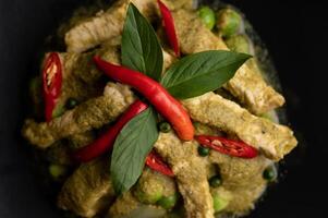 cerdo al curry verde en plato negro foto