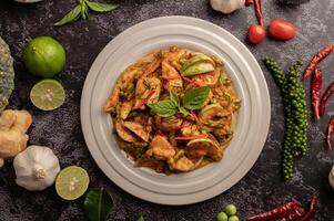 Dry green curry with chicken in white plates on black cement photo