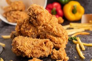 Fried Chicken and French Fries on Black Cement Floor. photo