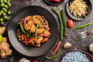 Stir-fried spicy Catfish in black plate with spices on black cement. photo