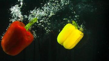 Photo of fresh vegetables falling in the water with bubble