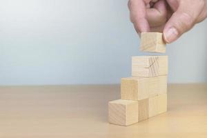 Hand arranging wood block stacking as step stair on wooden table photo