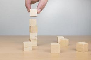 Hand arranging wood block stacking as step stair on wooden table photo