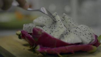 Close up woman's hand poked a piece of prepared dragon fruit to eat. video