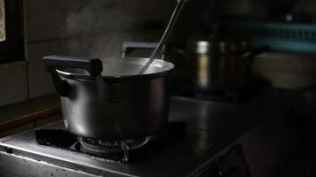 panela de cozinha fervendo feijão verde a mão da mãe mexendo com uma concha. video