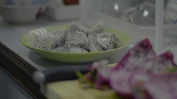 la mano de la mujer metió un trozo de fruta del dragón preparada en un plato. video