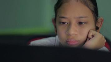 gelangweiltes asiatisches Schulmädchen, das zu Hause online auf dem Laptop lernt. video