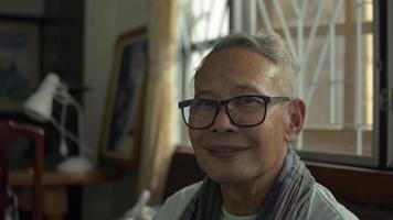 Portrait healthy grandfather looking at camera in living room. video