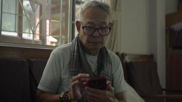 Hombre mayor que usa el teléfono móvil para la comunicación social en línea en casa video