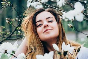 pretty girl in garden enjoys blooming magnolia trees photo