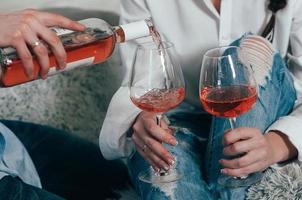 un hombre llena vasos con vino rosado de una botella foto