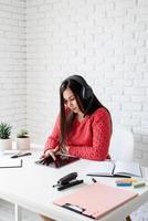 Young woman in black headphones teaching english online using tablet photo