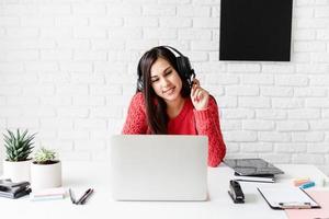 Young latin woman in black headphones teaching english online photo