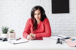 Young woman in black headphones teaching english online using tablet photo