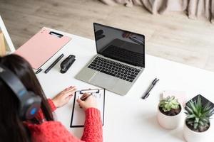 Young latin woman in black headphones teaching english online photo