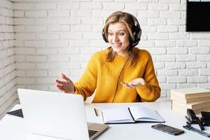 mujer joven, en, negro, auriculares, estudiar, en línea, usar la computadora portátil