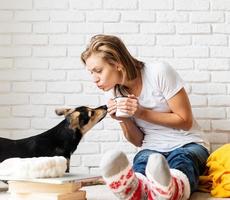 mujer sentada en el suelo con sus perros tomando café foto