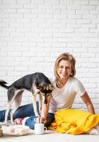 woman in yellow plaid sitting on the floor playing with her dogs photo