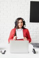 Joven mujer latina en auriculares negros enseñando inglés en línea foto