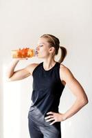 young blond woman drinking water after workout photo