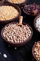 Various dried legumes in wooden bowls on wooden background photo