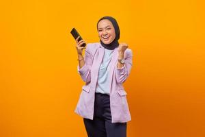 Cheerful asian woman showing smartphone and celebrating luc photo