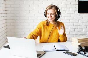 Young woman in black headphones studying online using laptop photo