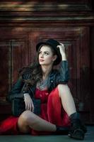 Young beautiful brunette woman with red short dress and black hat photo