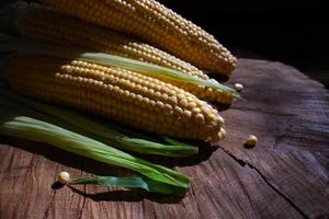mazorcas de maíz con hojas sobre fondo de madera. comida vegetal fresca