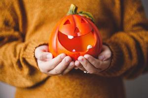 Halloween pumpkin lamp in children's hands. photo