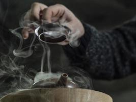 close-up male hand opens the lid of a clay teapot photo