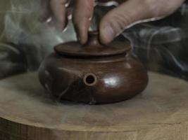 close-up male hand closed the lid of a clay teapot made of yixing clay photo