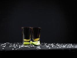 Two shots tequila gold with juicy lime and sea salt