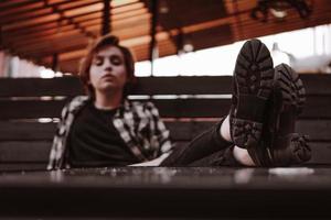 Young woman with short red hair in a bar put her legs on table photo