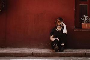 Retrato de una bella mujer sentada en el suelo sobre la pared roja foto