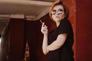 Girl with short red hair and mirror sunglasses smoking cigarette photo