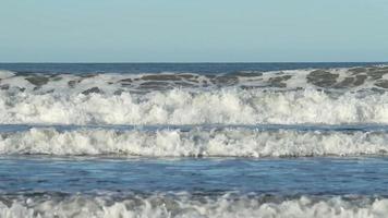 Ocean wave crashing on sandy shore.
